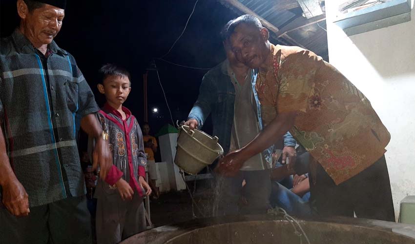 PANAS - Sejumlah warga Desa Watutulis, Kecamatan Prambon, Sidoarjo mendatangi sumur yang ada di makam desa setempat untuk merasakan panas air sumur yang mencapai 42 derajar selsius, Sabtu (28/12/2019) malam