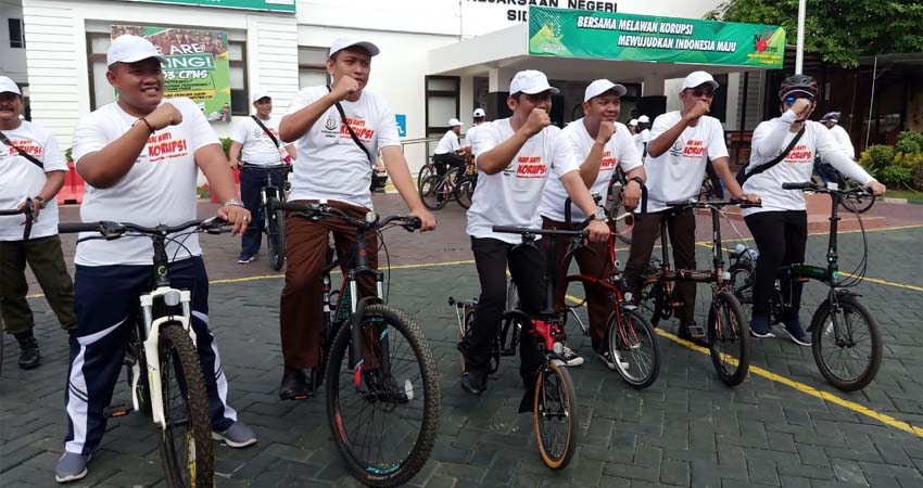 GOWES - Kepala Kejari Sidoarjo, Setiawab Budi Cahyono menggunakan sepeda Brompton didampingi para Kasi dan stafnya menuju SMP Negeri 1 dan SMK Negeri 1 Sidoarjo dengan cara gowes (ngonthel) dalam memperingati Hari Anti Korupsi Sedunia, Senin (09/12/2019)