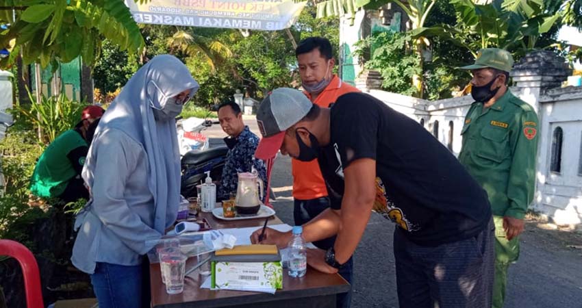 Tim relawan Desa Lemujut mengawasi pengguna jalan sedang mengisi form identitas di pos check point (gus)