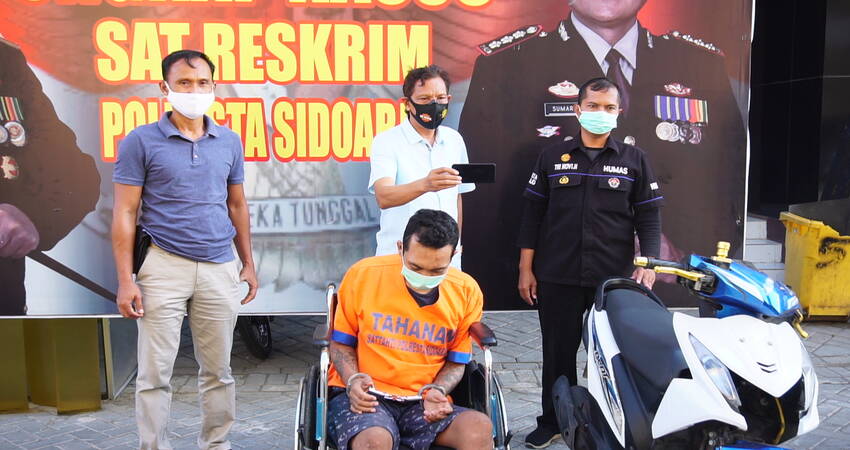 DITEMBAK: Kedua kaki tersangka perampasan motor, M Zaki Nurdin (24) warga Mojokerto ditembak kakinya dipamerkan bersama barang bukti motor Honda Beat rampasannya di Polresta Sidoarjo, Selasa (13/10/2020) sore.